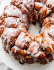 The Best Monkey Bread Recipe covered in a white glaze on a white plate.