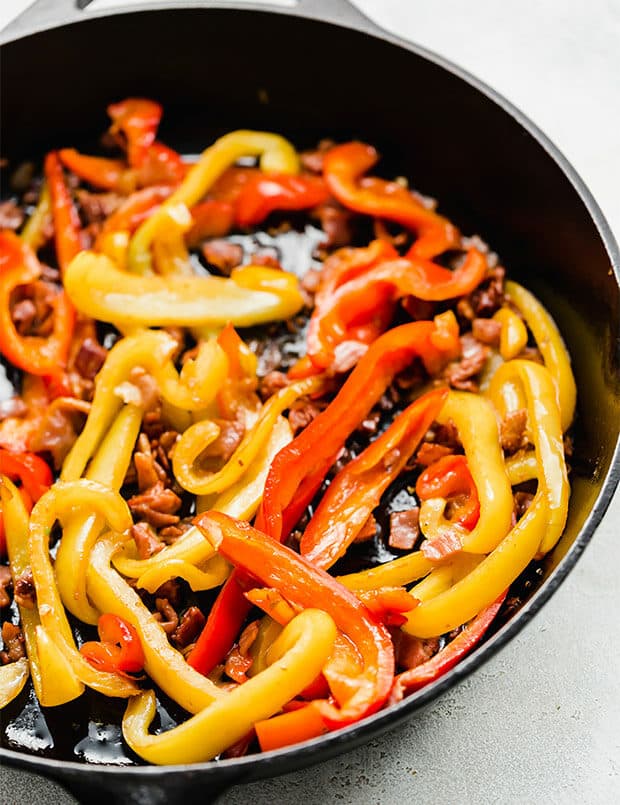 A skillet with sliced red and yellow peppers. 