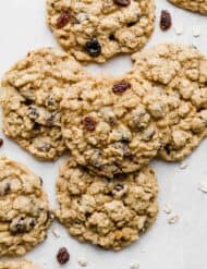 Soft Oatmeal Raisin Cookies stacked in a small pile on a light gray background.