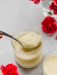 A spoon scooping out tapioca pudding from a glass jar.