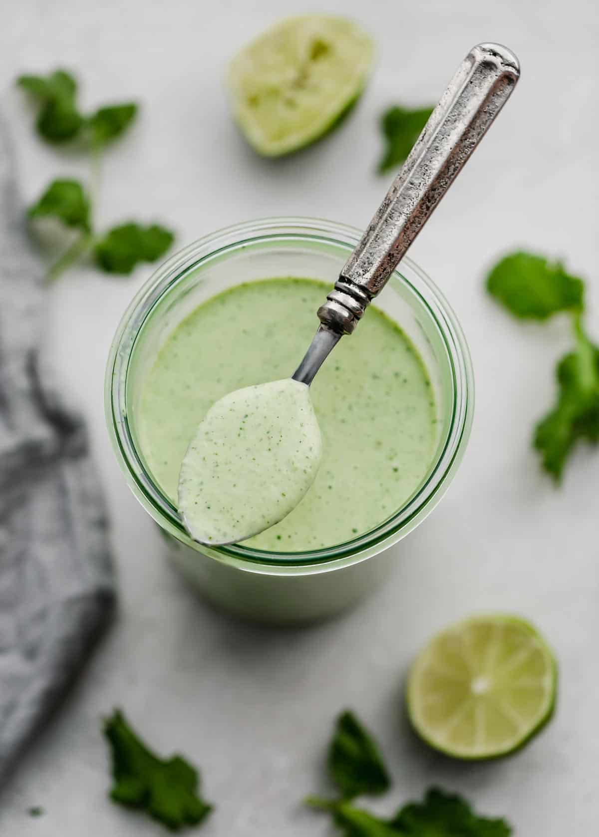 Cafe Rio Cilantro Lime Dressing in a glass jar with a spoon holding some of the creamy dressing.