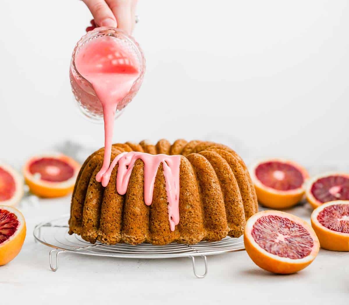 Blood Orange Glaze being drizzled over a blood orange cardamom bundt cake.
