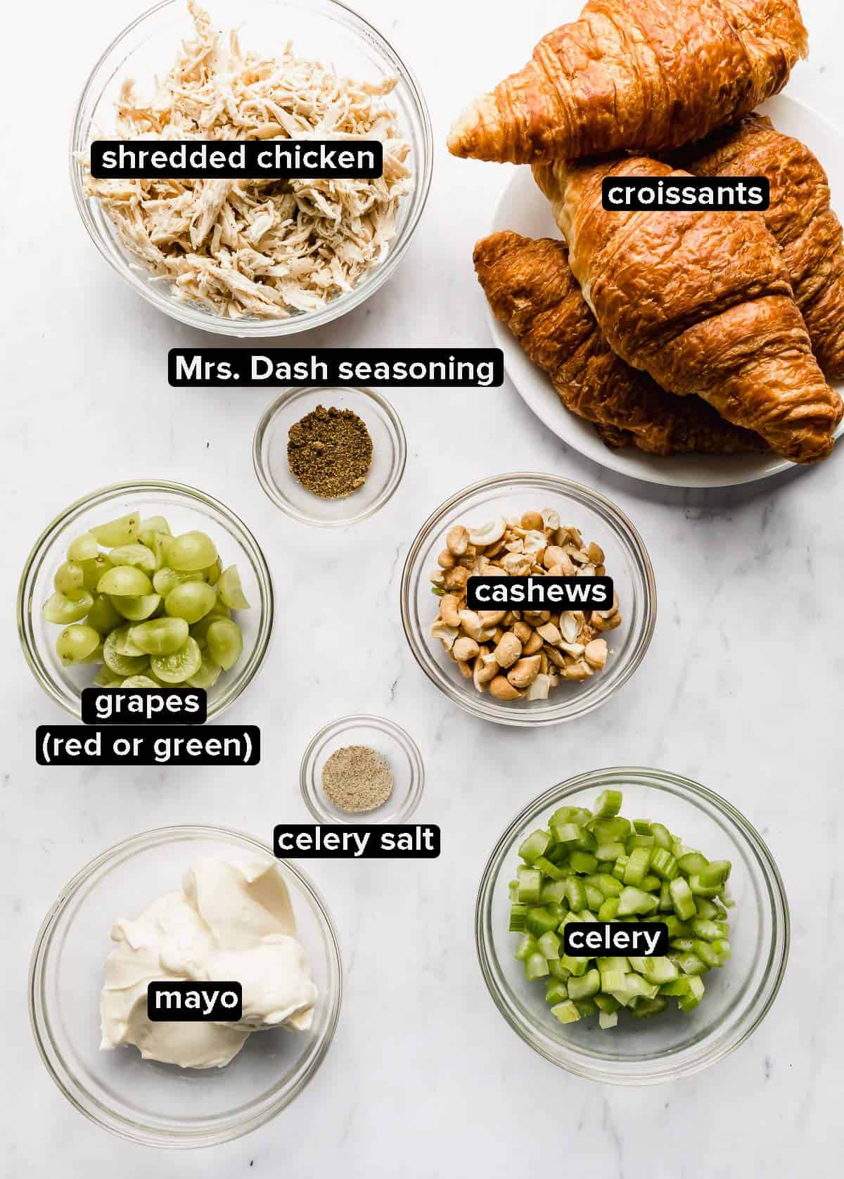 Chicken Salad Sandwich Recipe ingredients in glass bowls on a white marble background.