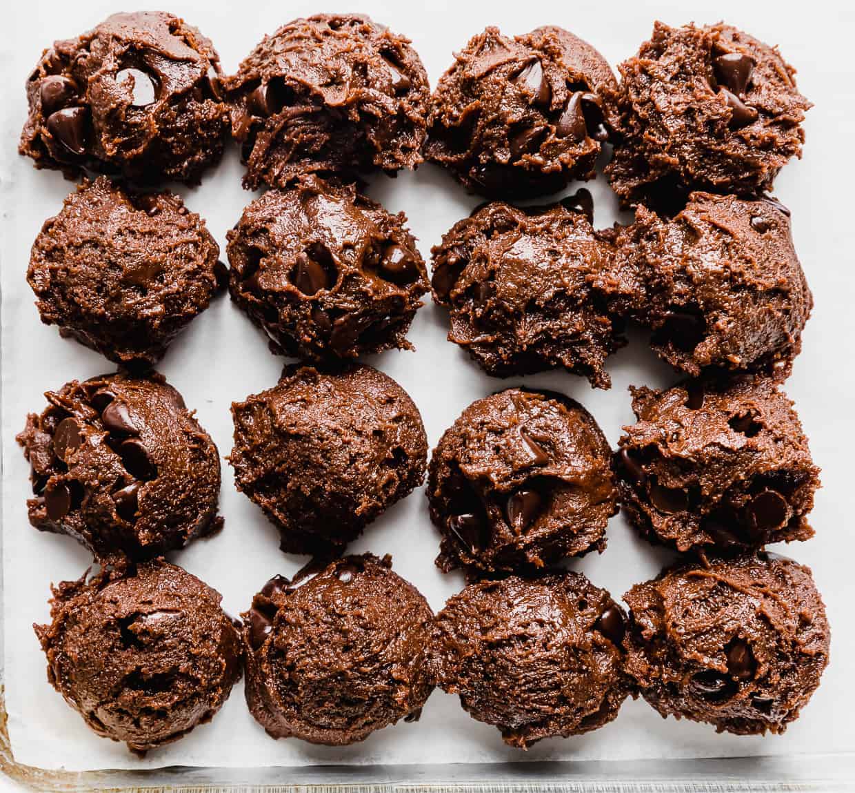 Double Chocolate Chip Cookie dough balls lined up on a white background.