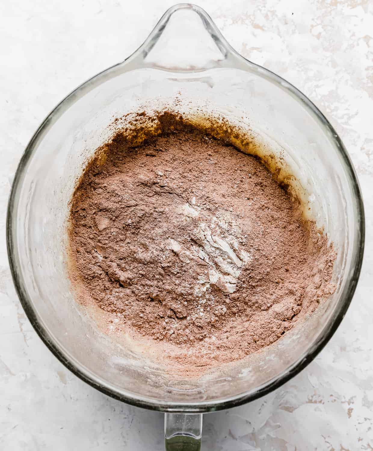 Cocoa powder mixed with flour in a glass stand mixer bowl.