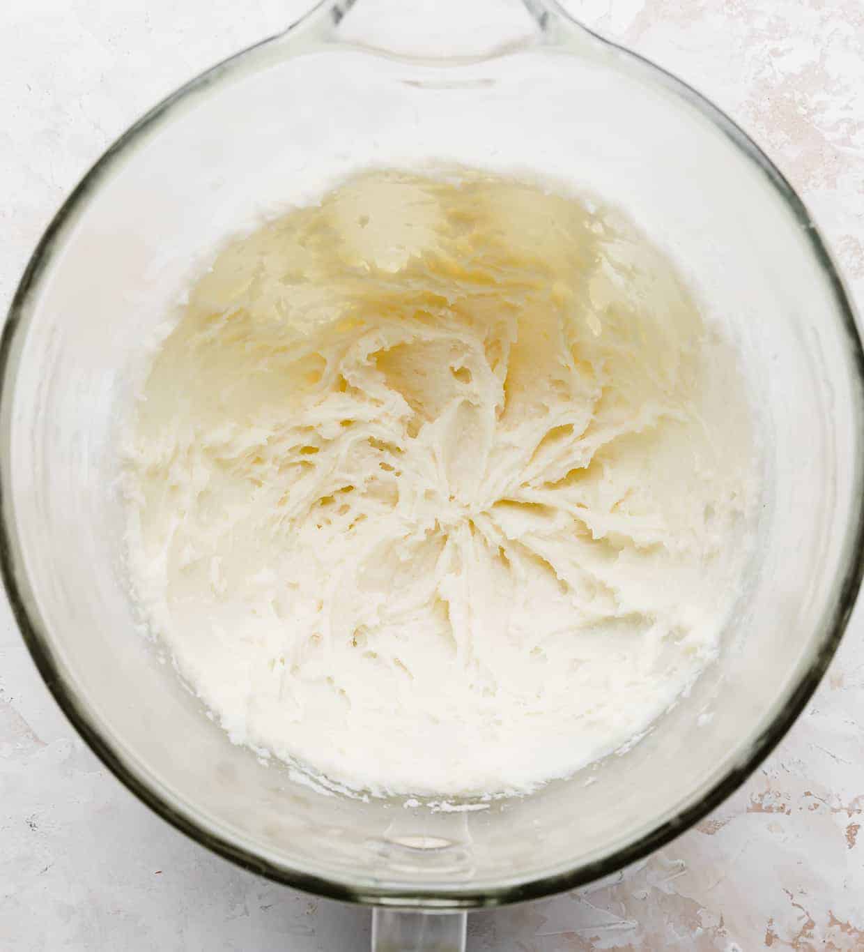Creamed sugar and cream cheese in a glass mixing bowl.