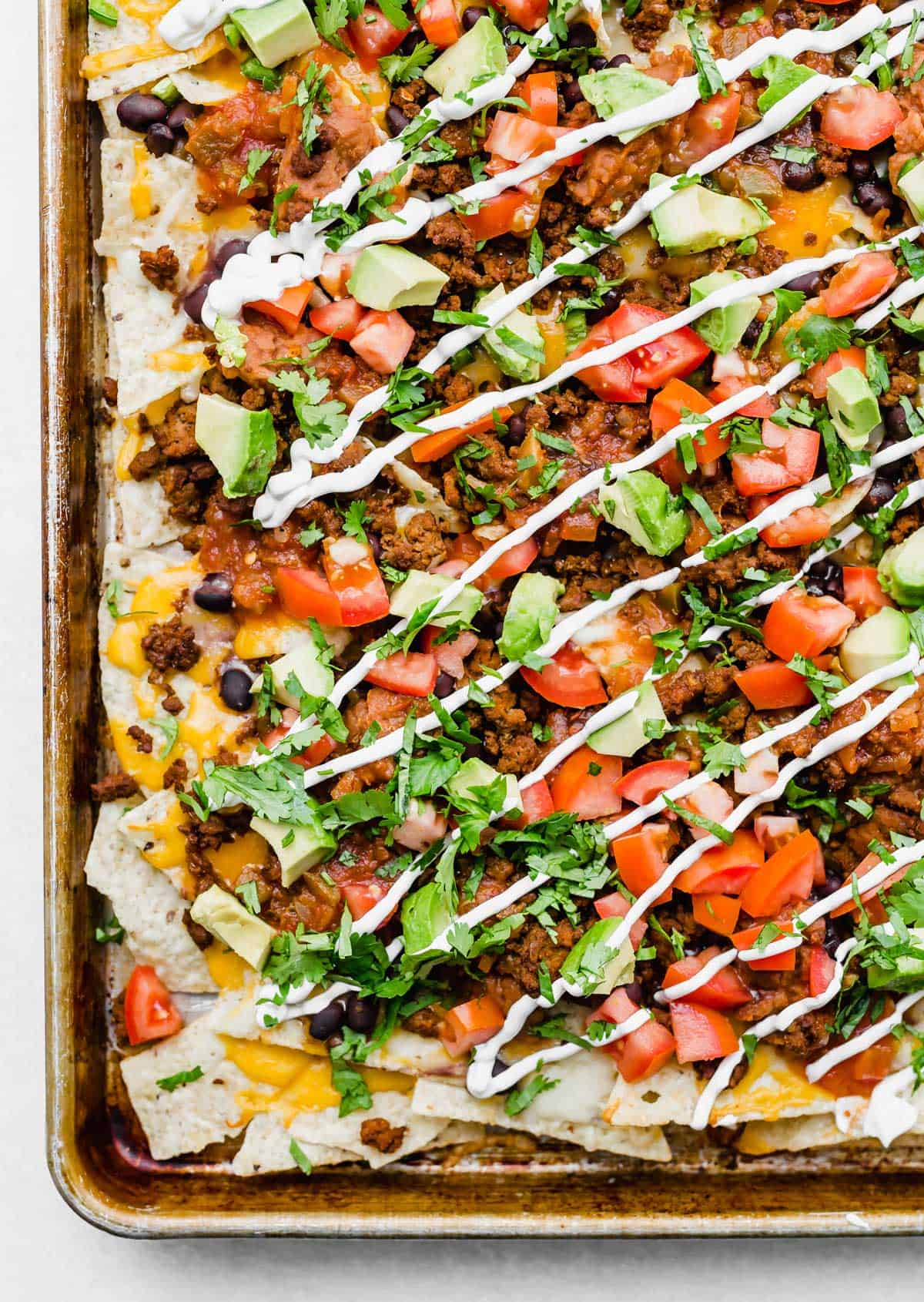 Loaded Nachos topped with tomatoes, avocado, salsa, taco meat, and sour cream.