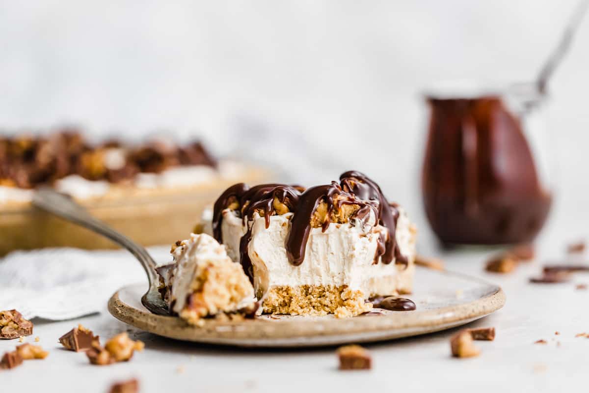 A No-Bake Peanut Butter Pie on a plate with a fork having cut into the tip of the pie slice.