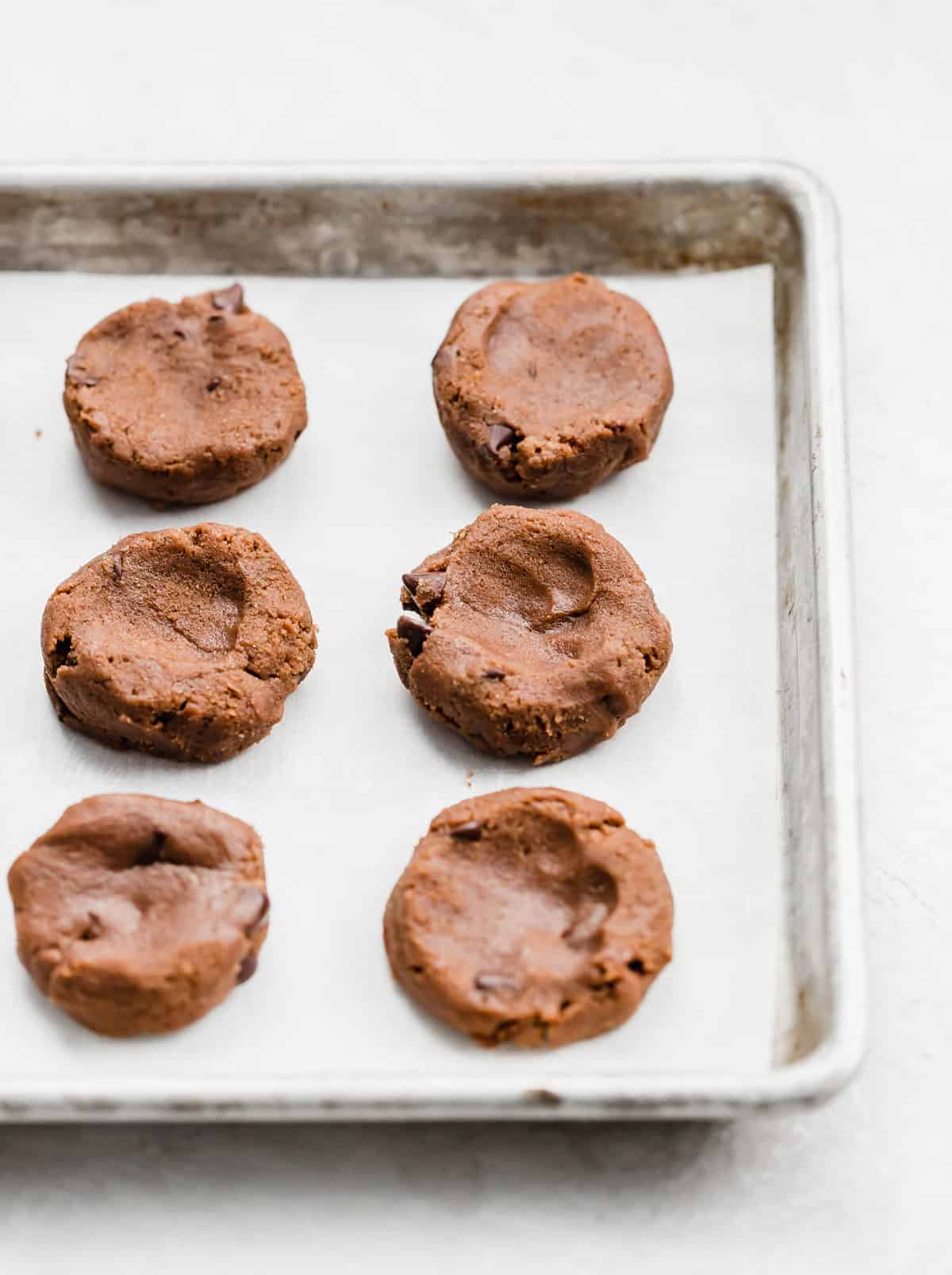 Nutella cookie batter portioned into round blobs on a baking sheet.