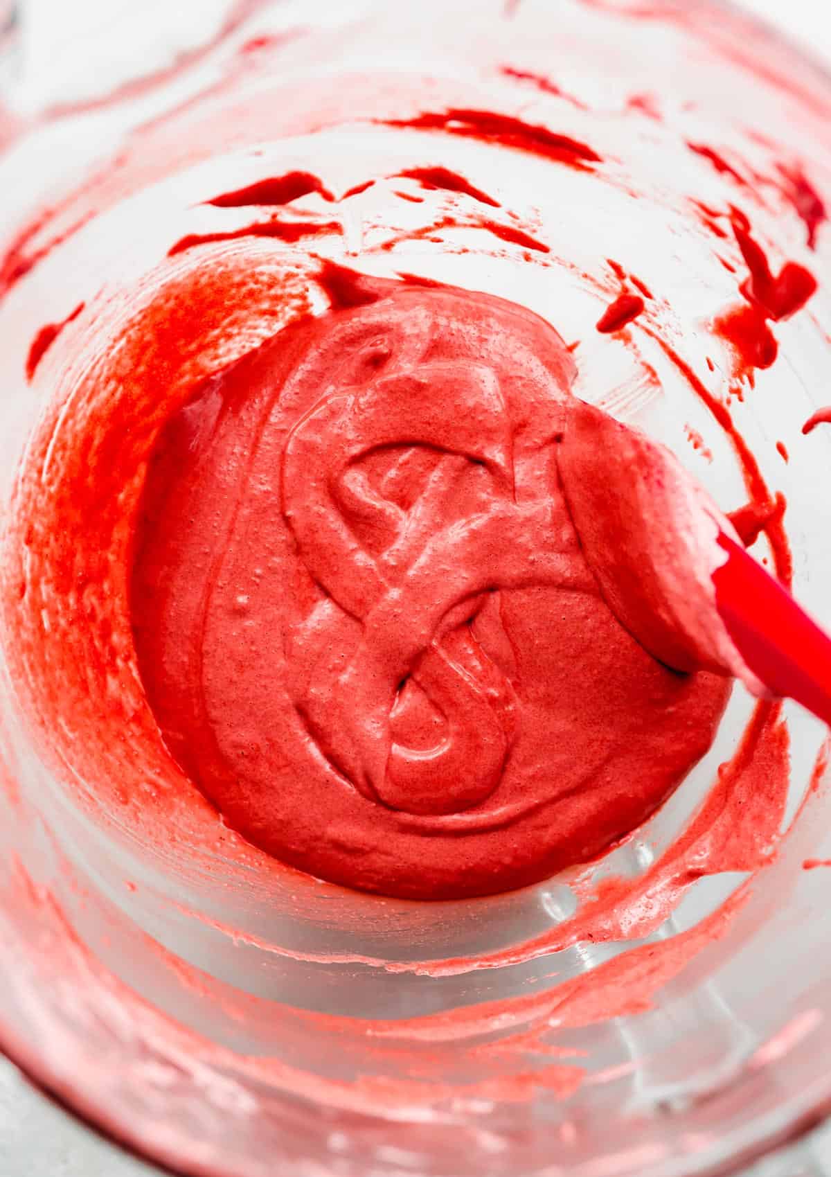 A Red Velvet Macaron batter forming a figure "8" in a glass bowl. 