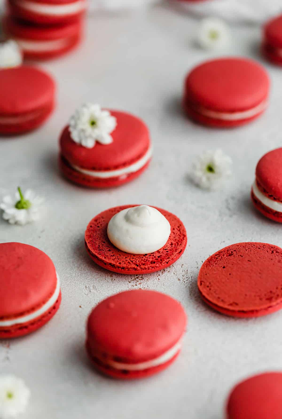 White cream cheese frosting filled Red Velvet Macarons on a gray background.