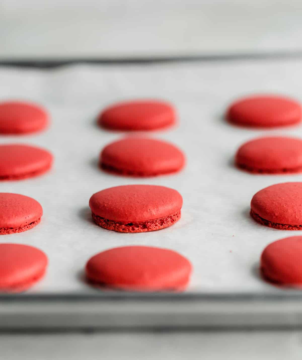 Baked Red Velvet Macarons on a white parchment lined baking sheet.