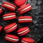 Red Velvet Macarons filled with a cream cheese frosting on a gray metal background.