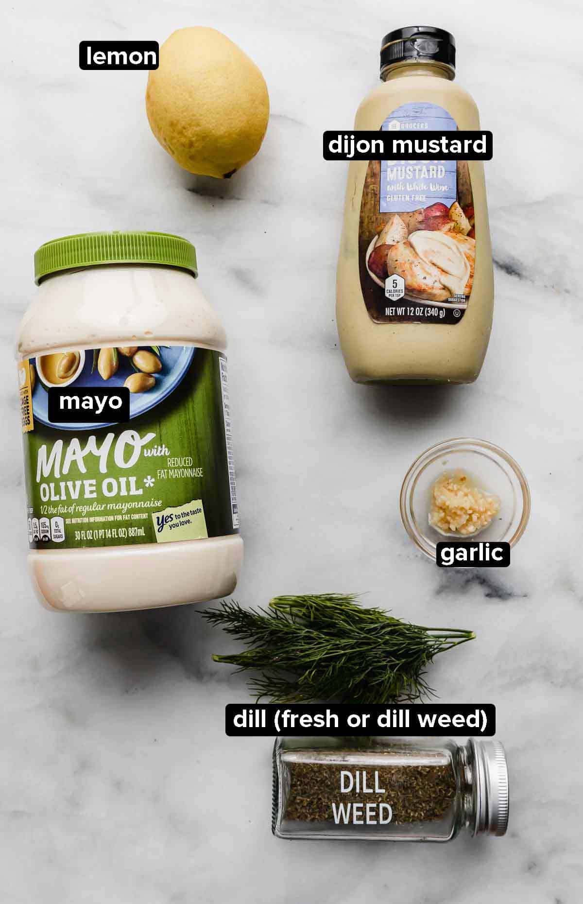 Mayo, dijon mustard, dill, garlic on a white background; these are the ingredients used to make a dill sauce for salmon burgers.