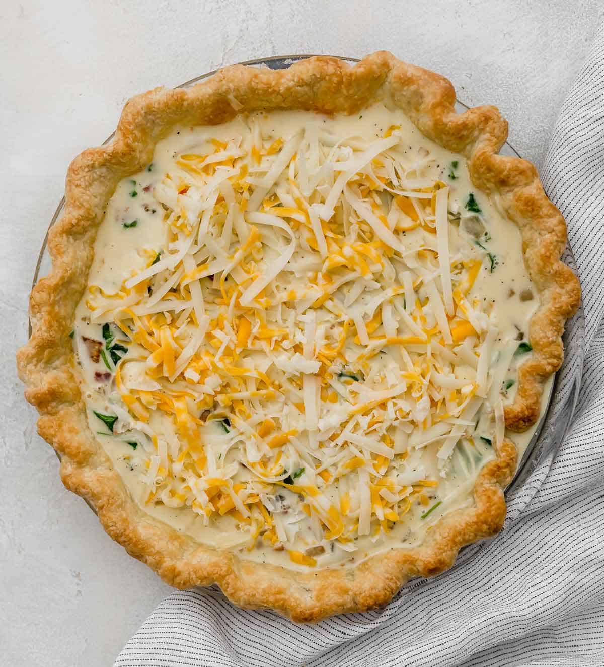 An unbaked Spinach and Bacon Quiche in a homemade pie crust.