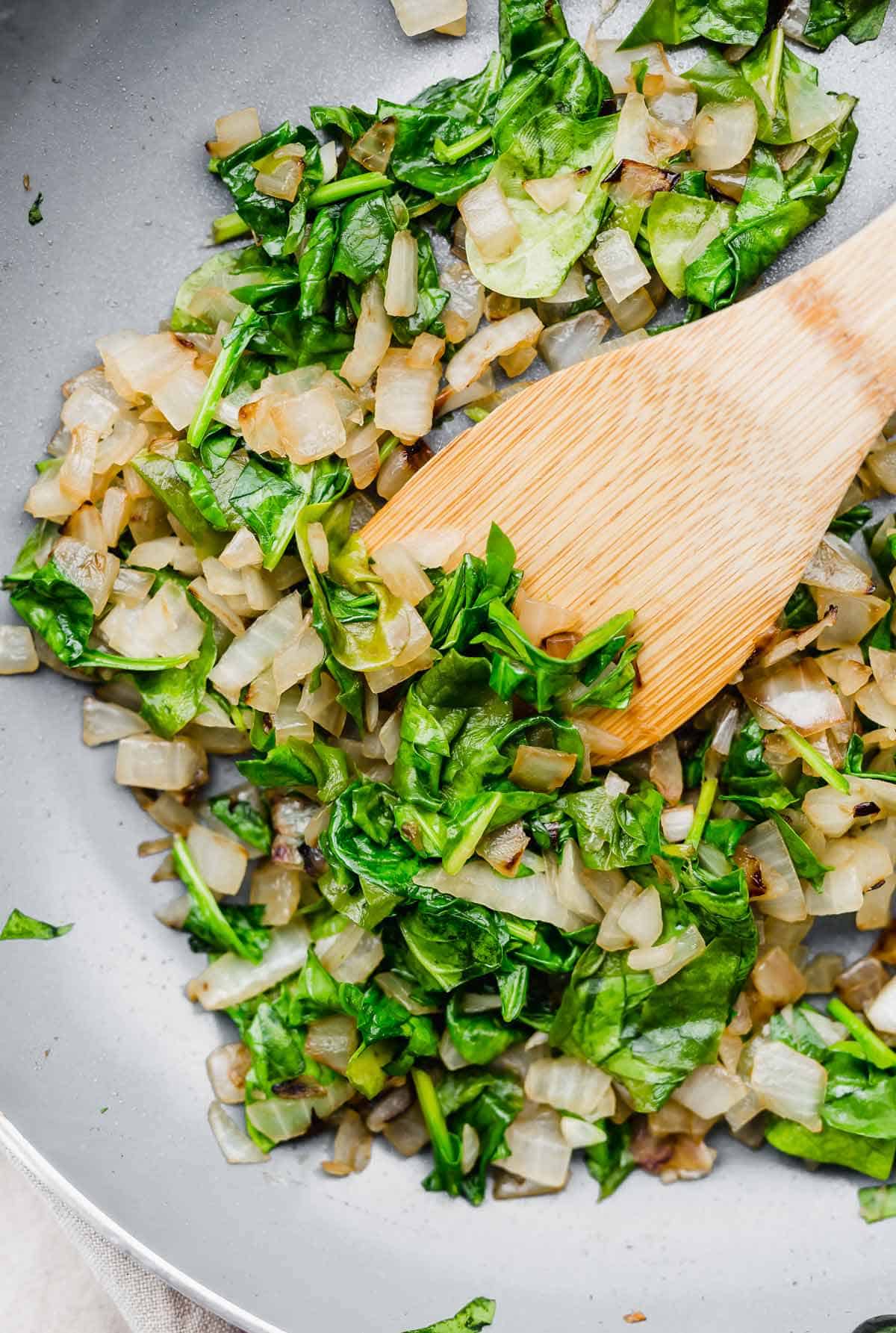 Spinach and onion mixture in a gray skillet.