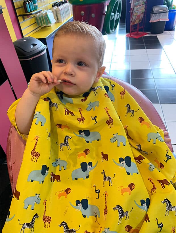 Little boy eating a sucker while getting hair cut.