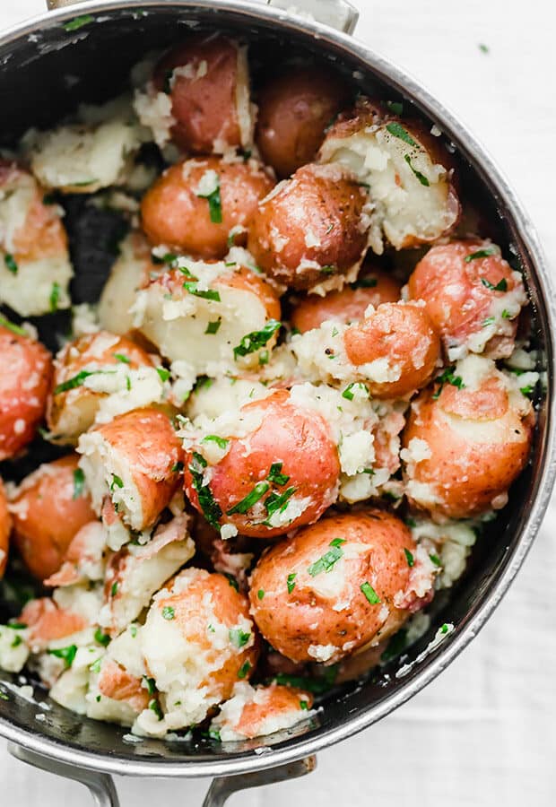 A close up photo of parsley potatoes in a black pot. 