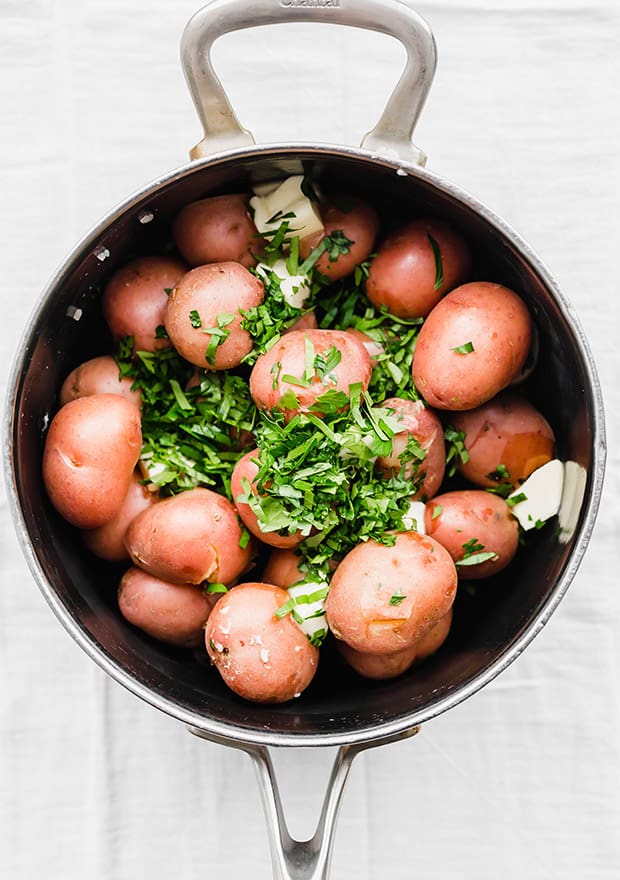 Red potatoes, butter, and chopped parsley in a pot.