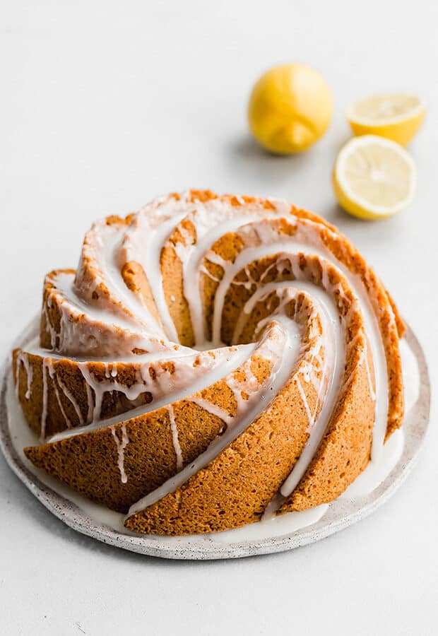 A ,Lemon Poppy Seed Bundt Cake covered in a lemon glaze against a white background.