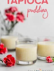A small glass cup full of tapioca pudding, surrounded by pink flowers.