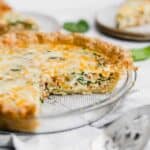 Spinach and Bacon Quiche or quiche Lorraine in a pie plate on a white background.