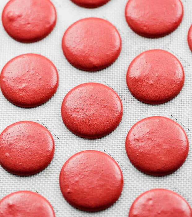 Red Velvet Macaron batter piped on a baking sheet, prior to baking.deixe os macarons descansar. A parte é importante, você precisa deixar os macarons piped descansar por 30-45 minutos para formar uma pele sobre os topos do macaron. Os macarons já não devem ser pirosos quando lhes tocas.cozinhar a 300 ° F durante 16-18 minutos. Remover e arrefecer durante 20 minutos antes de os Remover da folha de cozedura.