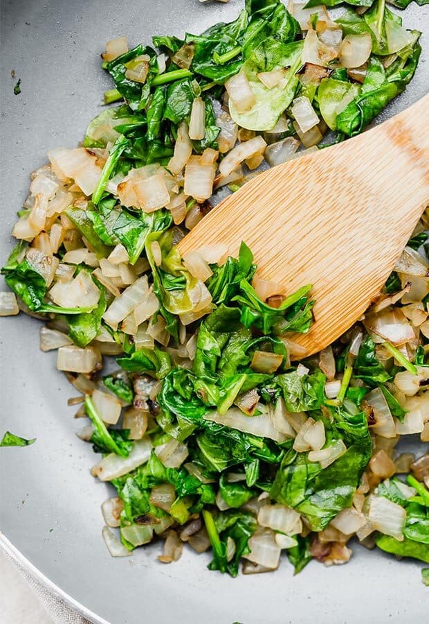 Sauted onions and spinach in a skillet.