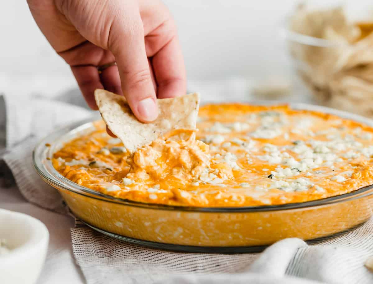 A tortilla dipping into the best buffalo chicken dip topped with bleu cheese.