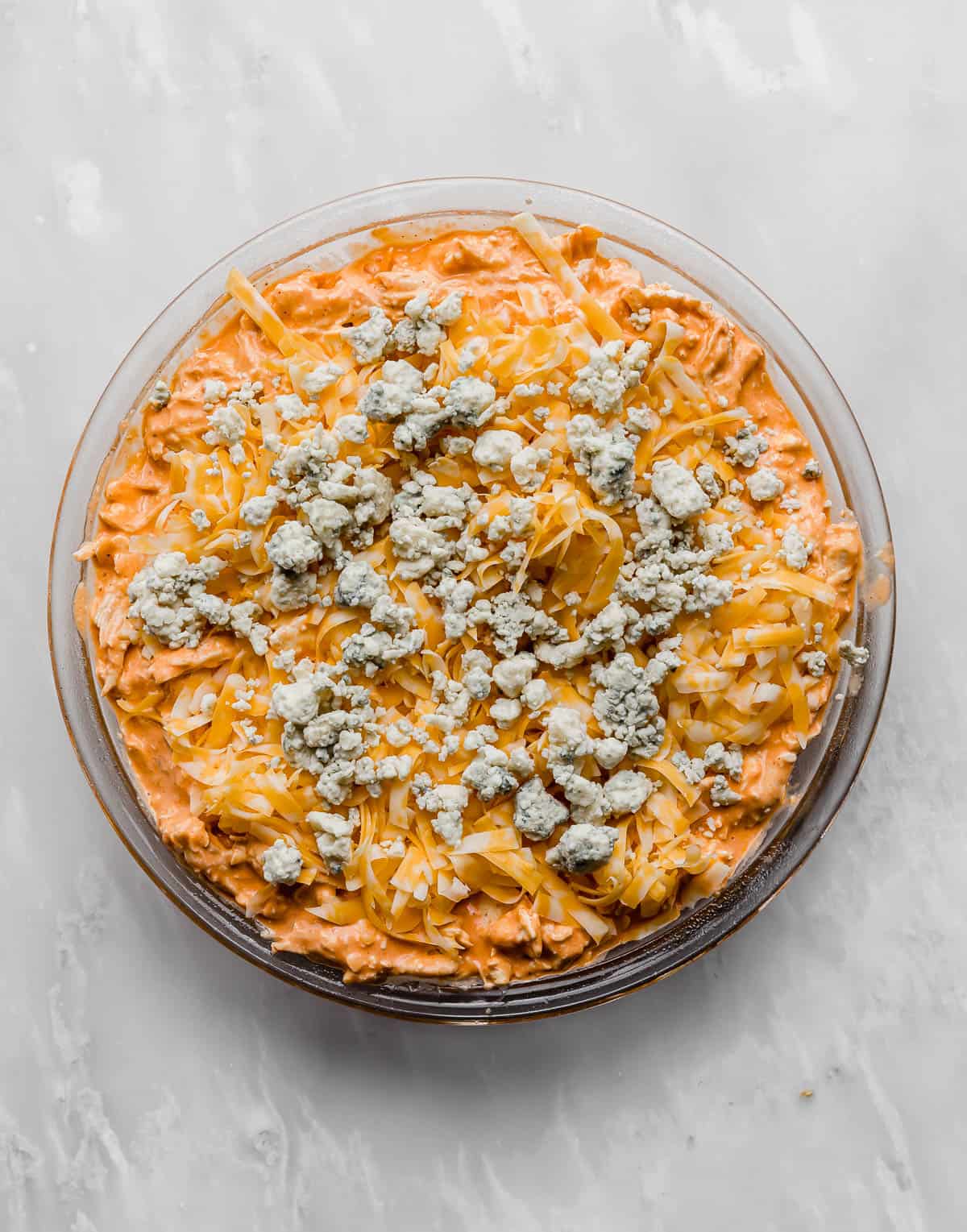 Buffalo Chicken Dip topped with blue cheese in a round dish.
