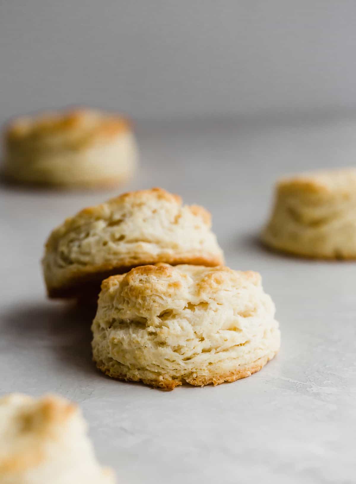 Two Flaky buttermilk biscuits on a light gray background.