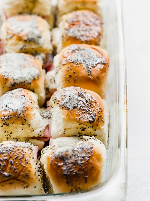 Baked ham and cheese sliders topped with a honey mustard poppyseed butter recipe.