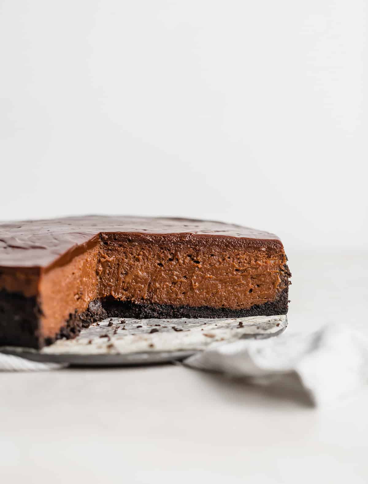 A Nutella Cheesecake with a slice removed, on a white background.