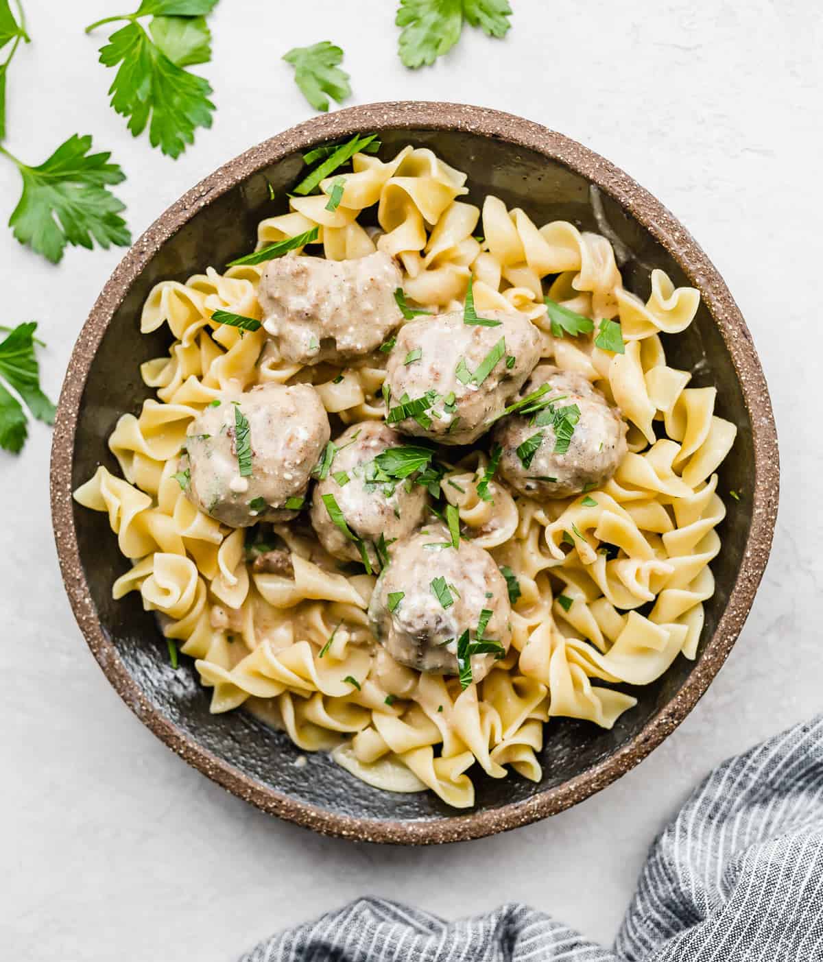 Swedish Meatballs on a bed of cooked egg noodles in a black plate.