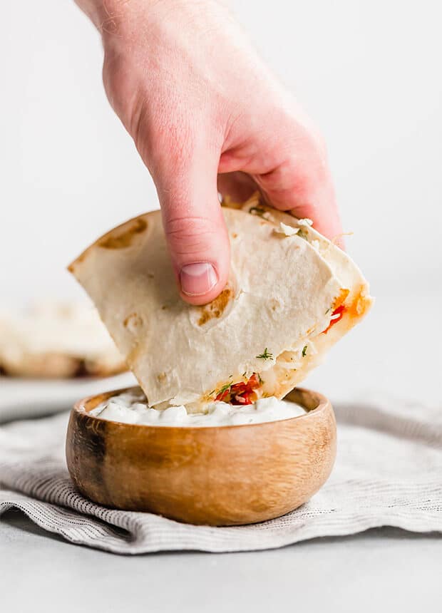 A Greek Quesadilla being dipped into homemade tzatziki sauce.