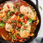 Roman Chicken with capers and red peppers in a black skillet.