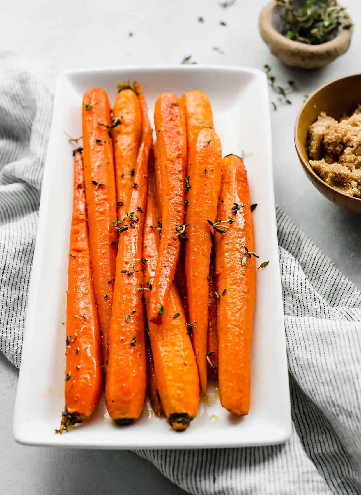 Brown Sugar Roasted Carrots topped with fresh thyme on a white plate.