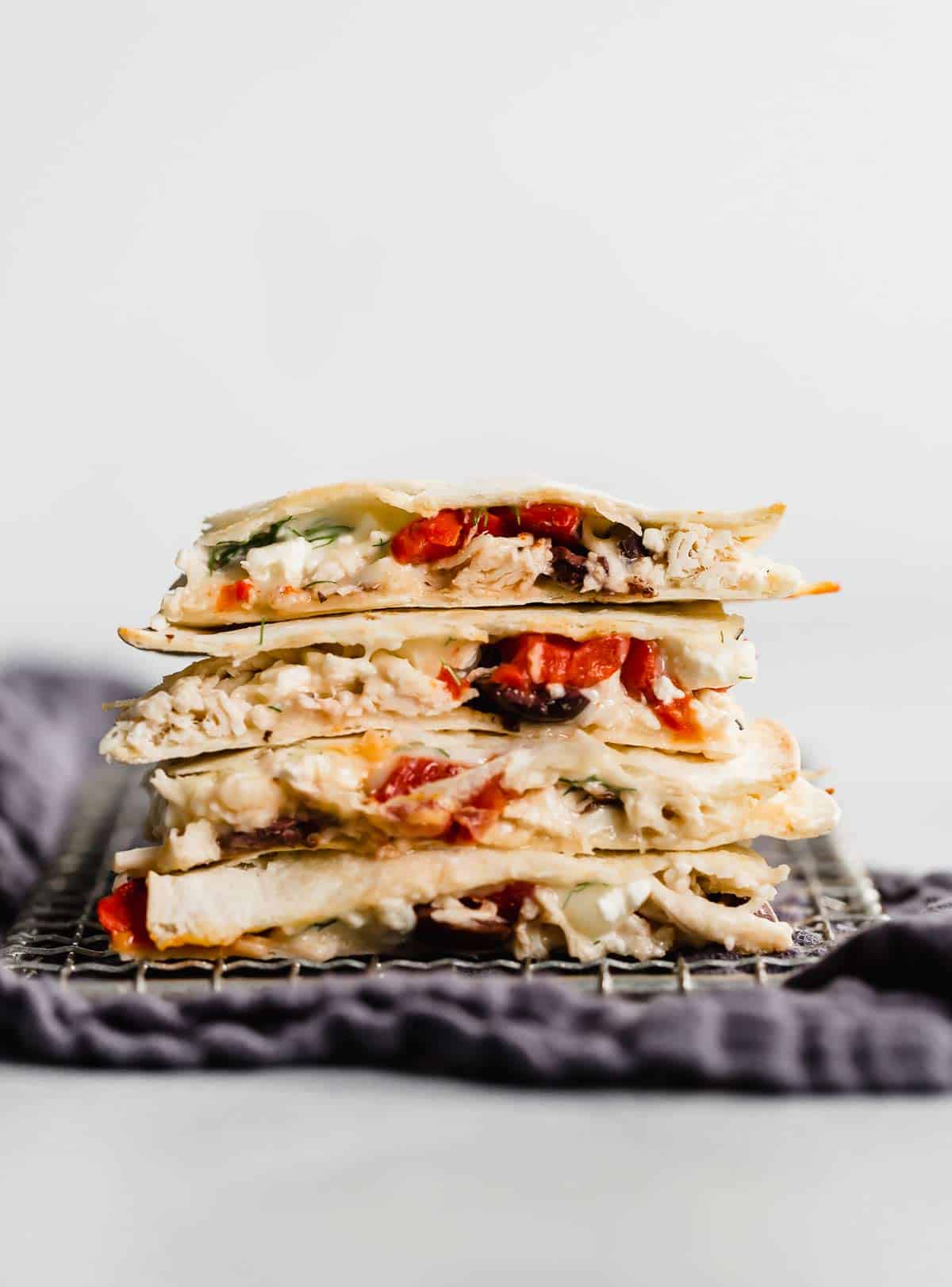 A Greek Quesadilla cut into quarters and stacked on top of each other against a white background.