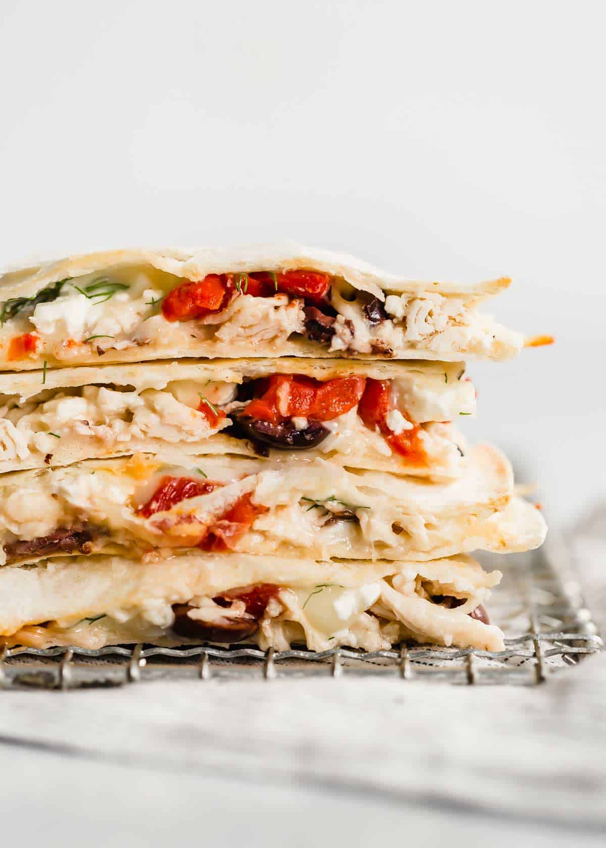 Close up photo of the a cut Greek Quesadilla with Kalamata olives, roasted red peppers, and shredded chicken.