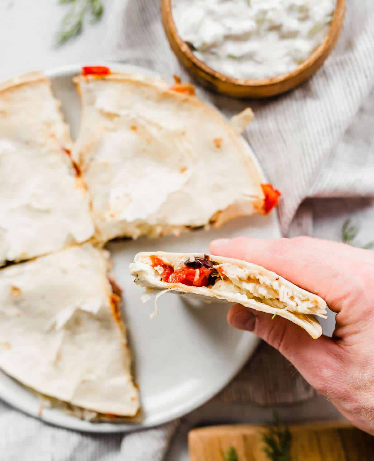 A hand holding a Greek Quesadillas.