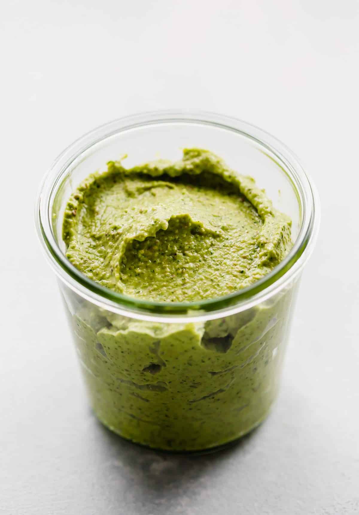A glass jar filled with a thick Green Sauce Recipe in it.