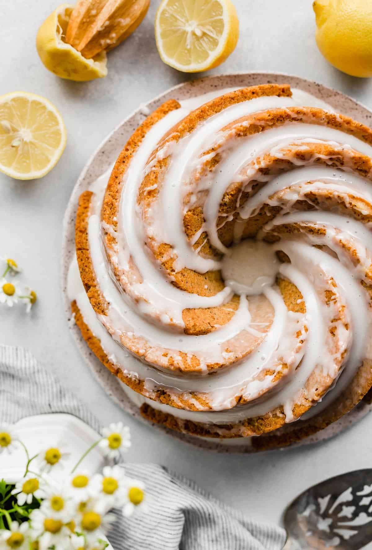 An overhead photo of a Lemon Poppy Seed Bundt Cake topped with a white glaze with sliced lemons around the cake.