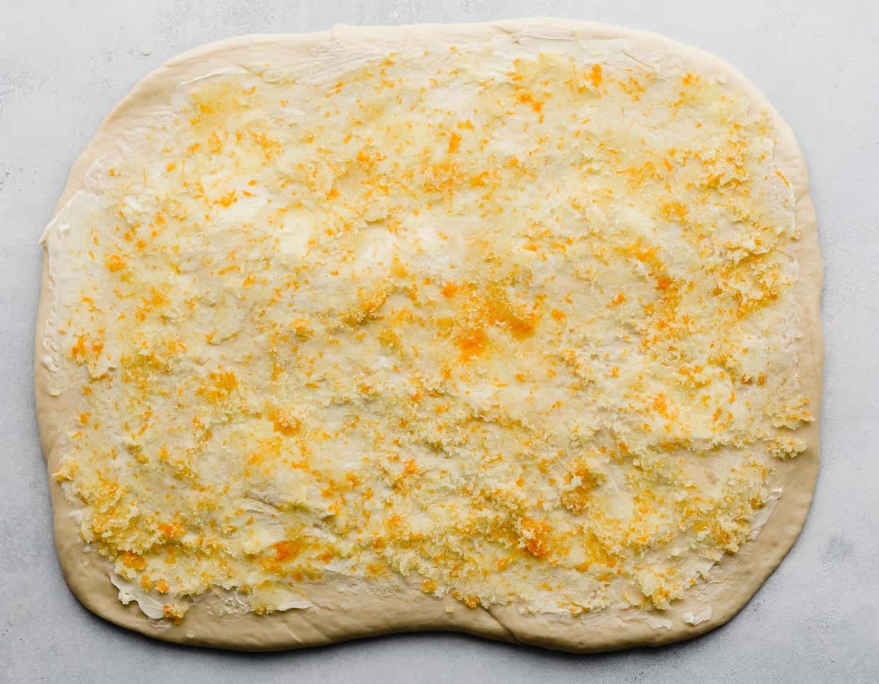 An orange sugar mixture spread over a rectangle sheet or rolled out dough.