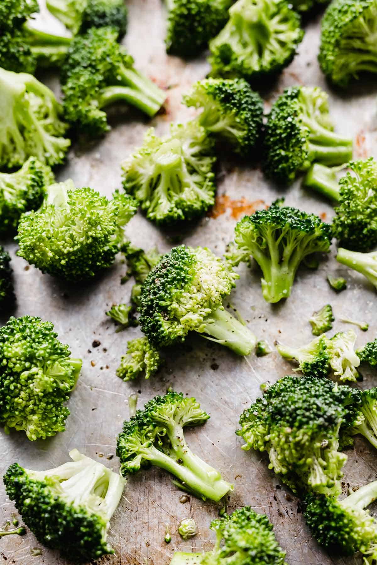 Raw and uncooked broccoli florets on a baking sheet.