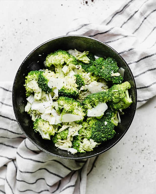 Overhead photo of broccoli Caesar salad in a black bowl.