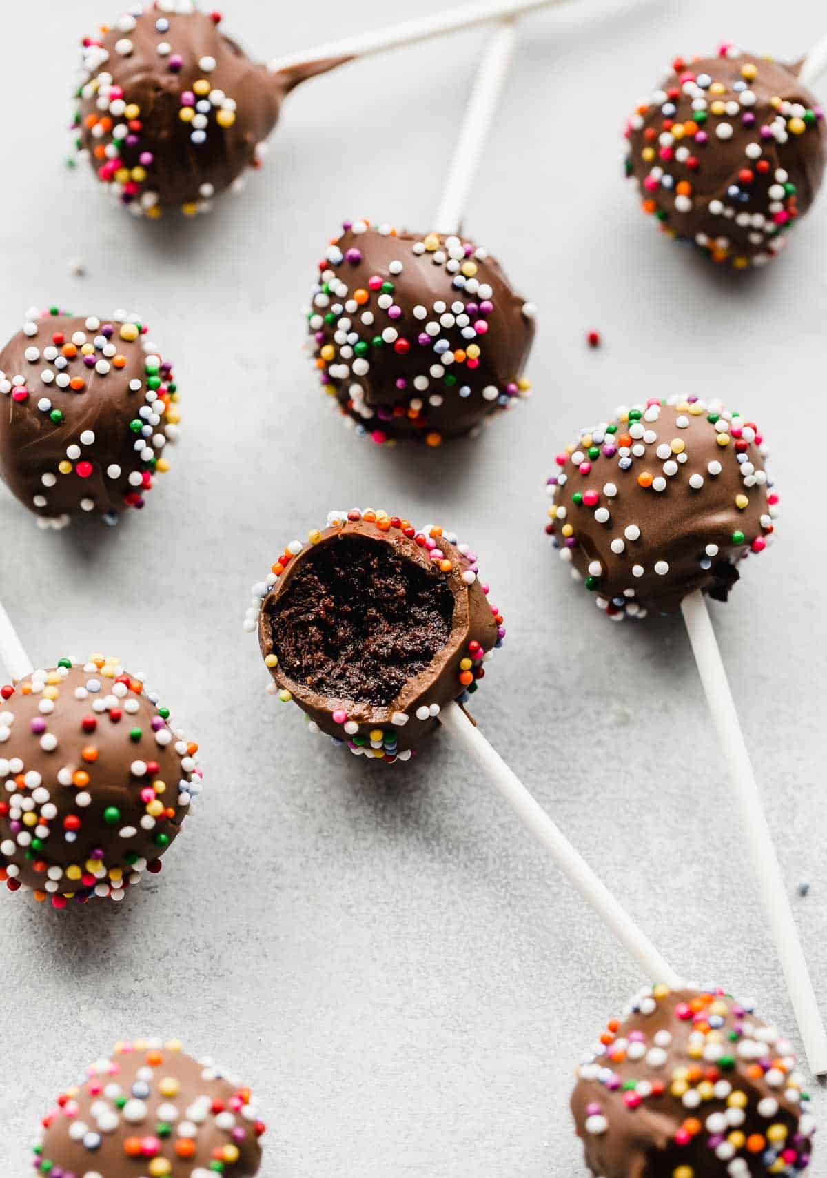 Sprinkle covered Chocolate Cake Pops on a white background.