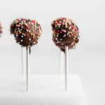 Chocolate Cake Pops covered in colorful sprinkles against a white background.