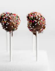 Chocolate Cake Pops covered in colorful sprinkles against a white background.