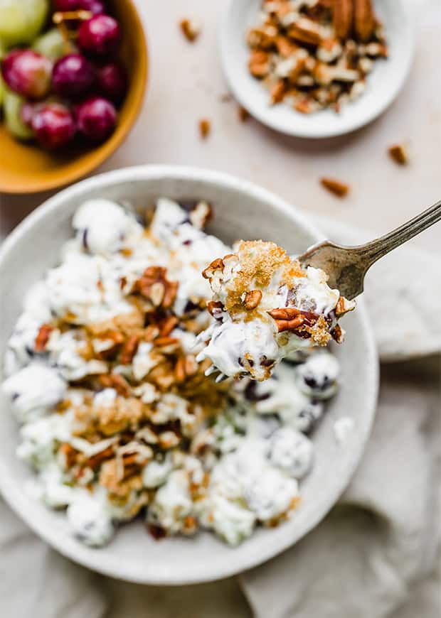 Creamy Grape Indulgence 9 A single fork holding a spoonful of creamy grape salad, highlighting the perfectly coated grapes and crunchy pecan pieces.
