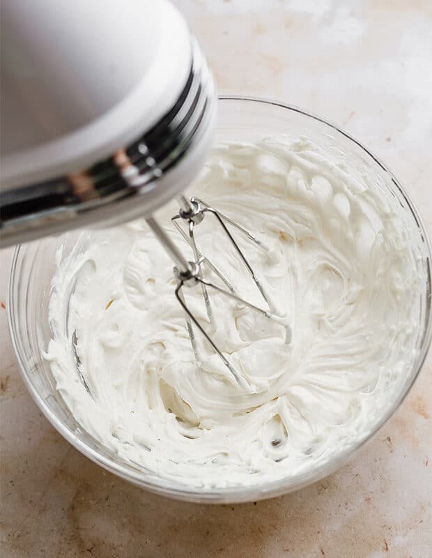 A hand mixer creaming the white dressing for the grape salad.